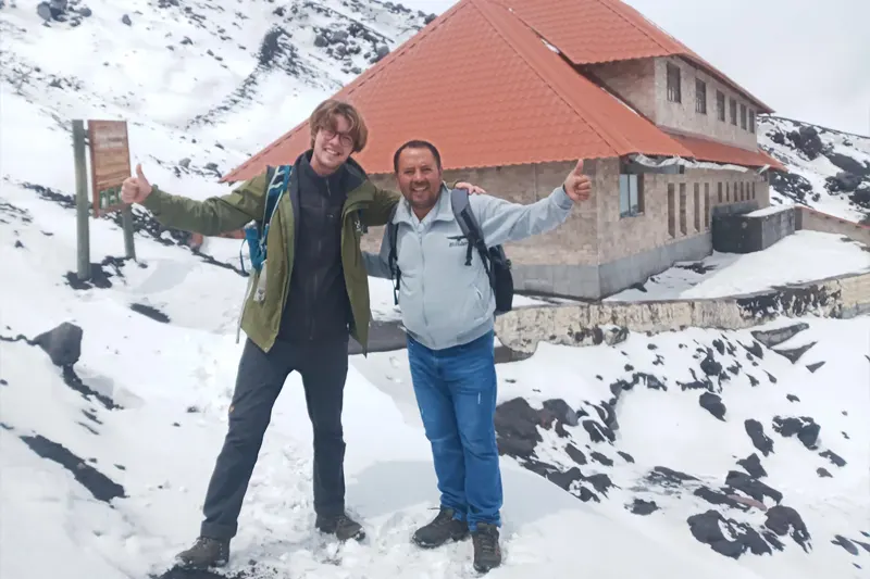 Marco Herrera with a traveler at José Rivas Refuge on the snowy slopes of Cotopaxi Volcano, Ecuador