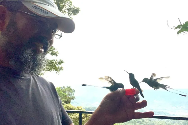 Marco Herrera feeding hummingbirds in the cloud forest of Mindo, Ecuador