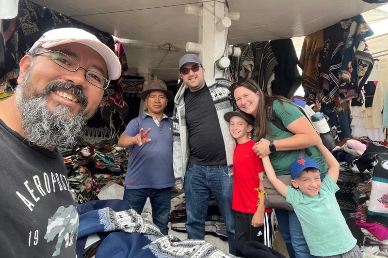 Marco Herrera with travelers and local vendors at Otavalo Indigenous Market, Ecuador